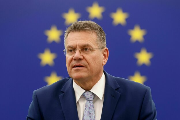 Porträt von Maros Sefcovic, ein Mann mit Anzug und Krawatte und ordentlichem Kurzhaarschnitt, dezente Brille vor dem EU-Logo