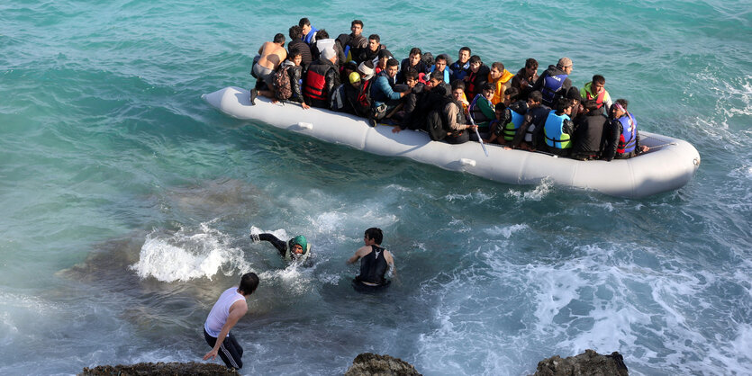 Ein voll besetztes Schlachboot an felsiger Küste