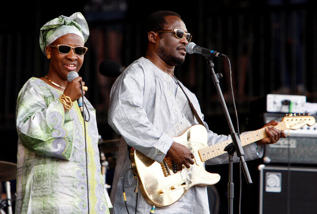 Amadou & Mariam bei einem Auftritt. Sie singen jeweils in ein Mikrofon, er spielt Gitarre