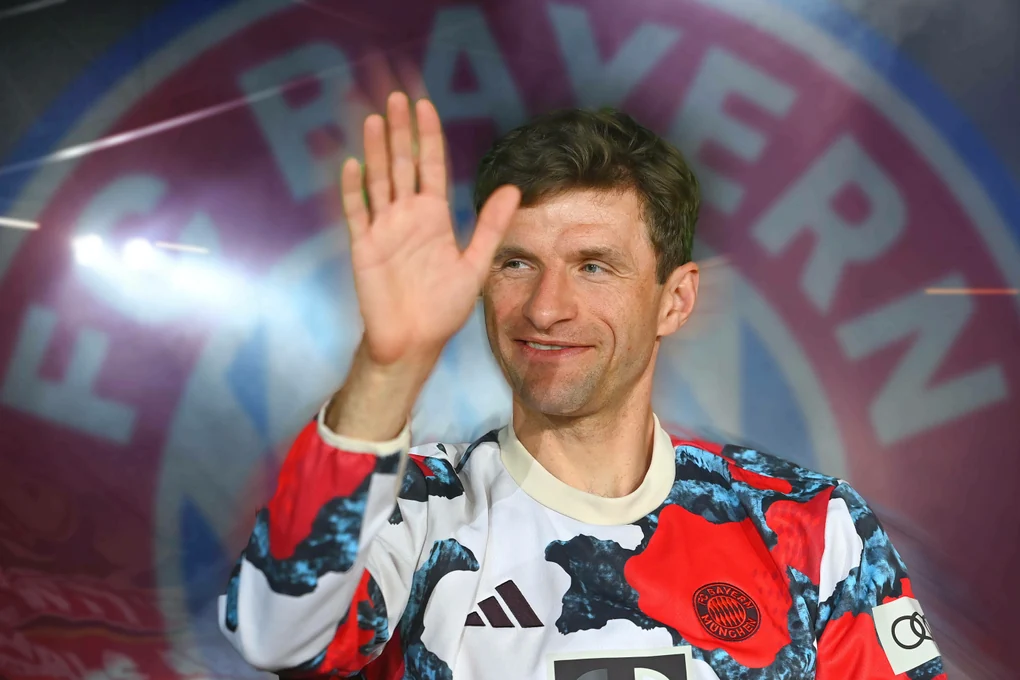 Fußballspieler Thomas Müller im FC Bayern-Trikot vor einem FC Bayern Emblem