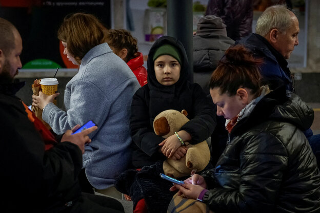 Ein Kind sitzt mit Kuscheltier im Arm in einer Metro-Station, um sich vor russischen Luftangriffen zu schützen.