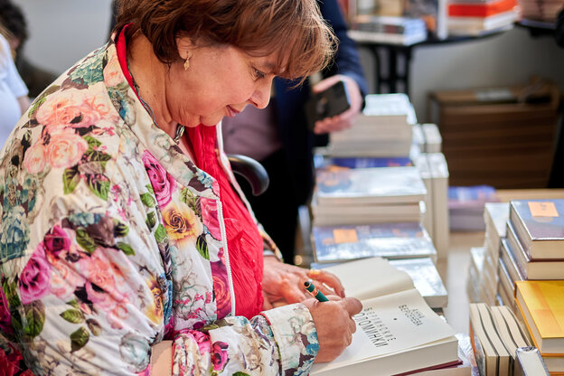 Eine Frau im geblümten Blouson signiert Bücher