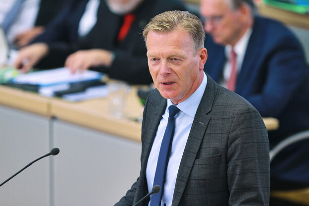 Ein Mann steht an einem Rednerpult und spricht ins Mikrofon