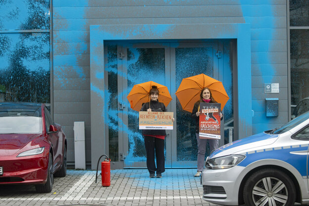 Protestaktion mit Farbe vor einer Teslafiliale.