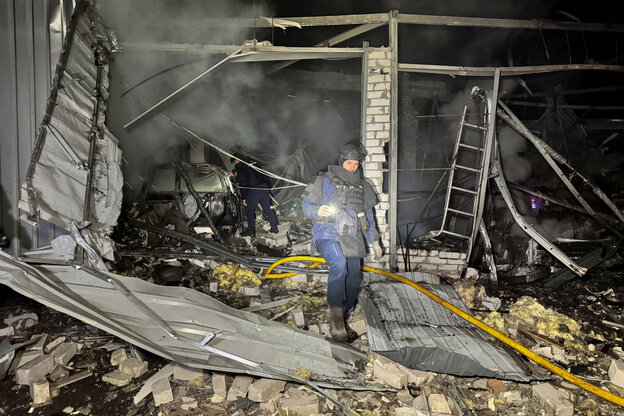 Eine Person in Schutzanzug inmitten der Überreste eines zerstörten Gebäudes
