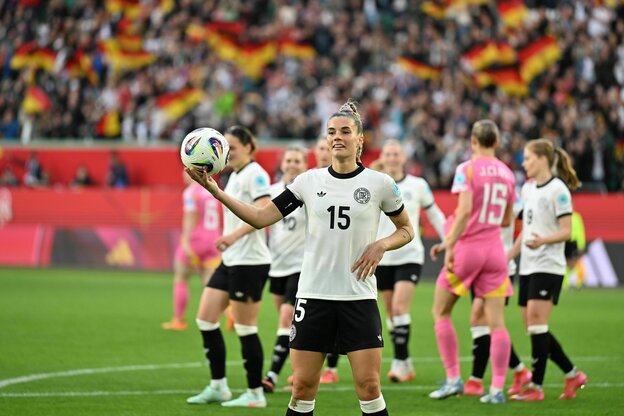 Selina Cerci posiert mit dem Ball in der rechten Hand vor der Kamera, im Hintergrund ihre Mitspielerinnen