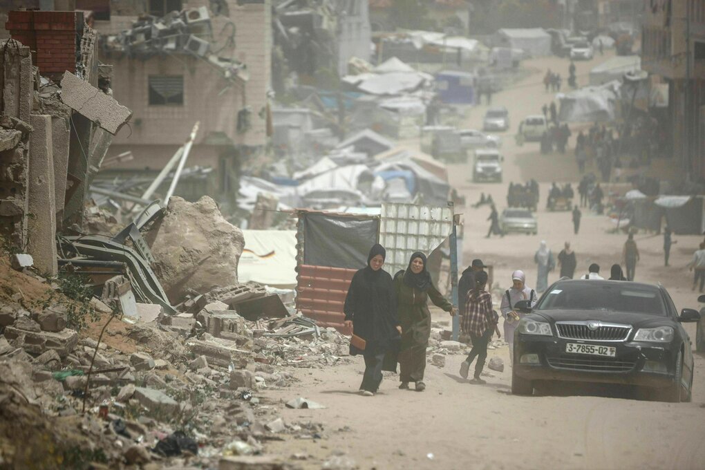 Palästinenser gehen während eines Staubsturms am 30. April 2025 in Gaza-Stadt zwischen Zelten und zerstörten Gebäuden eine Straße entlang