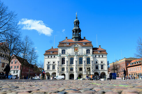 Blick über den kopfsteingepflasterten Marktplatz auf das historische Rathaus von Lüneburg