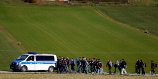 Flüchtlinge laufen hinter einem Polizeiauto her