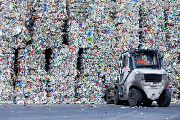 Ein Gabelstapler verlädt gepresstes Plastik auf einer Mülldeponie