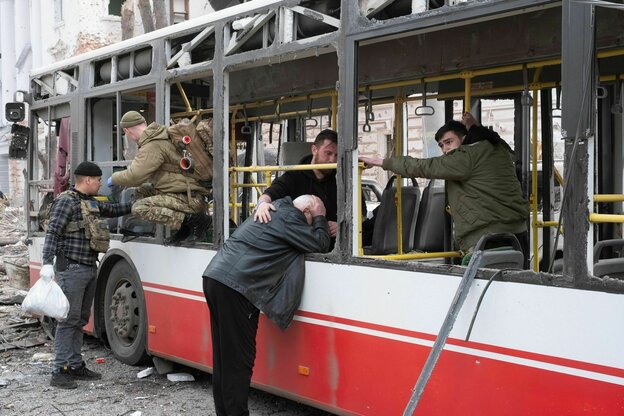 Ein Mann lehnt weinend an einem Bus, ein anderer Mann hat tröstend die Hand auf seine Schulter gelegt