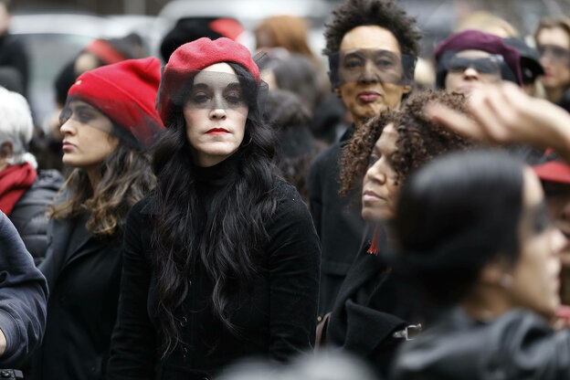 Eine Gruppe von Frauen sind in schwarz gekleidet und tragen rote Mützen und sethen mit ernstem Blick zusammen