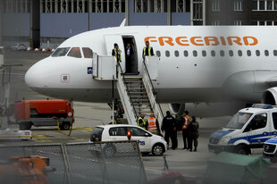 Polizisten bringen einen Mann in ein Flugzeug der türkischen Airline Freebird