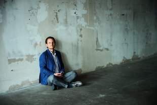 der Ex-Millionär Sebastian Klein sitzt auf einem Betonboden vor einer kahlen Betonwand