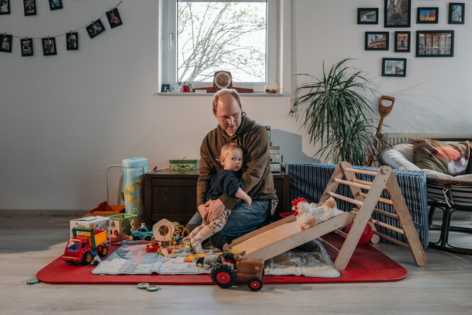Lasse Brandt sitzt mit seinem kleinen Kind in der Spielecke in seiner Wohnung