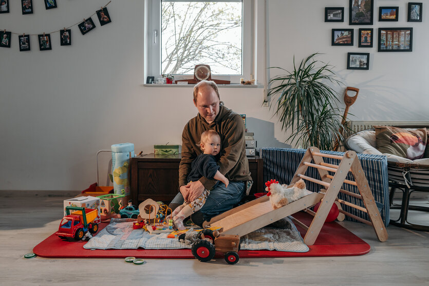Lasse Brandt sitzt mit seinem kleinen Kind in der Spielecke in seiner Wohnung