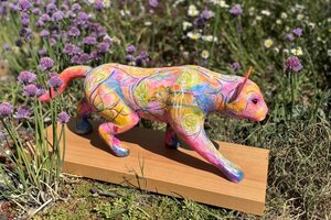 Zu sehen ist der Panterpreis, eine bunte Raubkatzen-Skulpur, in einer Blumenwiese stehend.