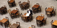 Ein Mann sitzt einsam an einem Tisch und liest Zeitung