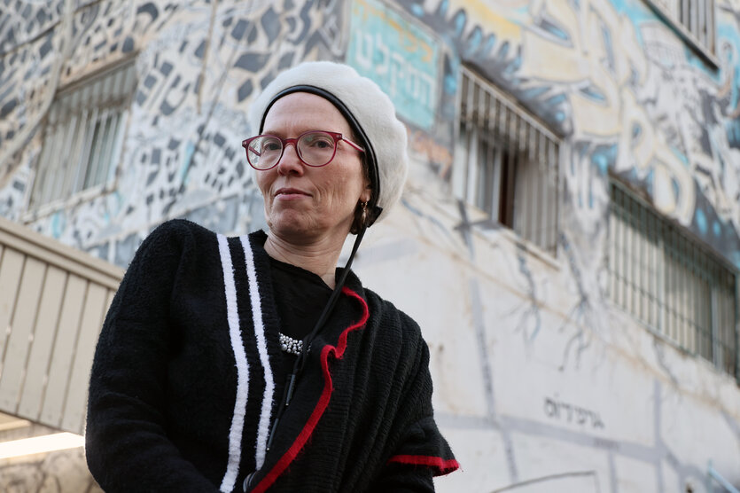 Frau mit weißer Fellmütze, roter Brille und dunklem Pullover: die Galeristin Noa Lea Cohen