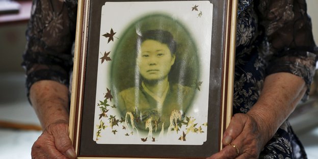 Jemand hält ein altes Foto von einer Asiatin in seinen Händen
