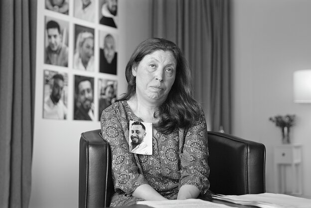 Emiş Gürbüz sitzt vor einer Wand mit Fotos. An ihrer Kleidung haftet ein Foto ihres ermordeten Sohns Sedat.