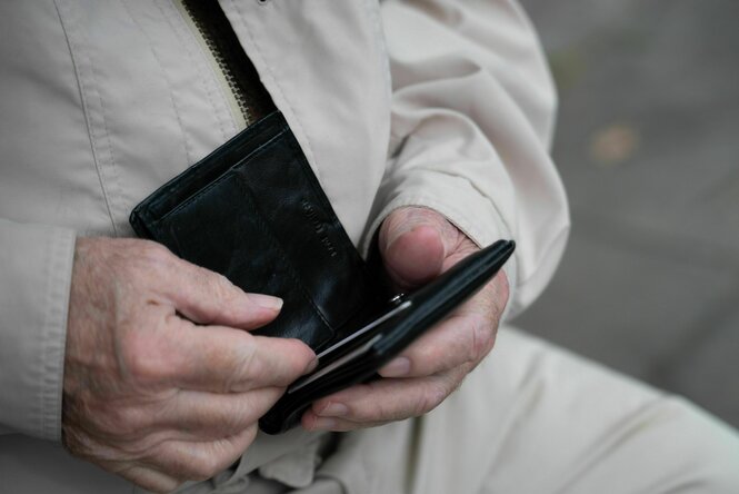 Ein Rentner hält sein leeres Portemonnaie in der Hand