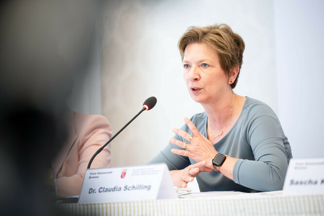Claudia Schilling sitzt bei einer Pressekonferenz hinter einem Mikrofon und spricht.