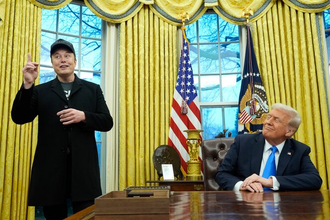 elon Musk gestikuliert vor gelben Vorhängen im Weißen Haus, und Donald Trump guckt zu