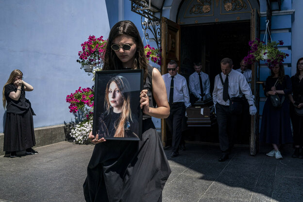 Frau verlässt mit einem Foto Victoria Amelinas eine Kirche, hinter ihr wird der Sarg herausgetragen