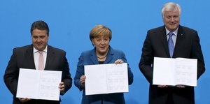 Sigmar Gabriel, Angela Merkel und Horst Seehofer stehen da und halten geöffnete Bücher hin - den Koalitionsvertrag