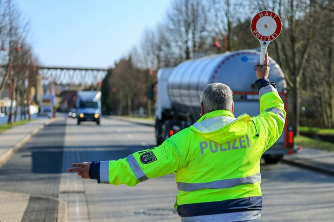 Ein Polizist in gelber Weste hält einen Transporter an