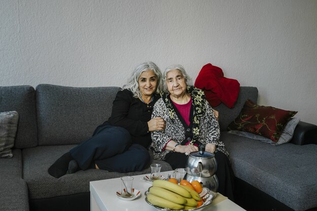 Zwei Frauen sitzen auf einem Sofa in einer Wohnung