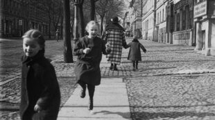 Historische Aufnahme von Kindern, die über Straßenpflaster in Berlin hüpfen