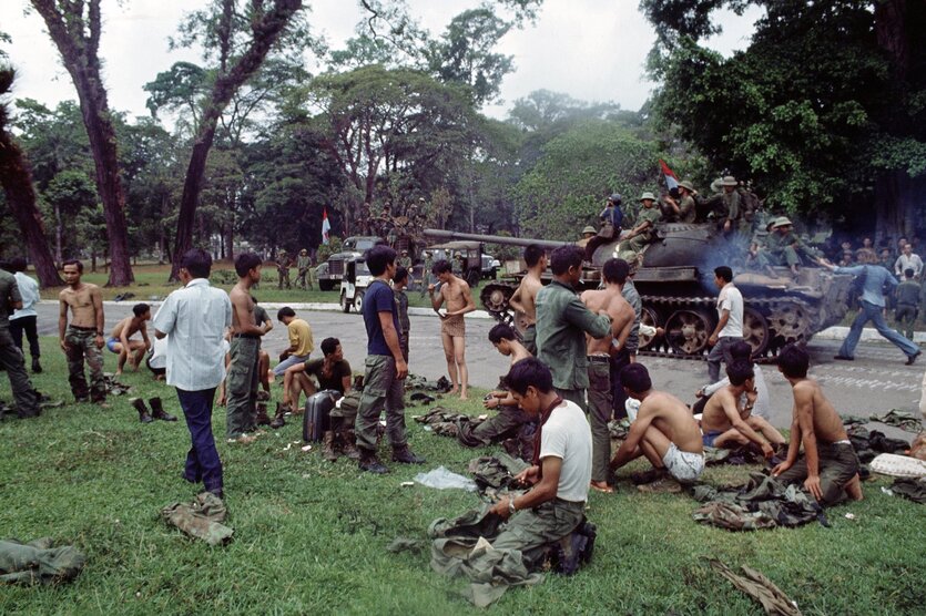 Saigon, 30. April 1975: Südvietnamesische Soldaten legen ihre Uniformen ab, während ein Panzer der nordvietnamesischen Armee vorbeifährt