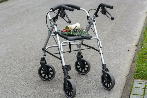 Ein Rollator mit Tannesnzweig und Trauerkerze auf einem Friedhof