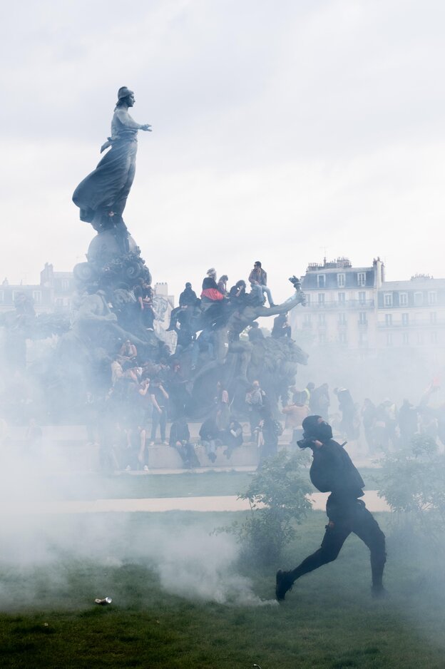 Demonstranten hocken auf einer Statur, die Szene in Protestnebel gehüllt