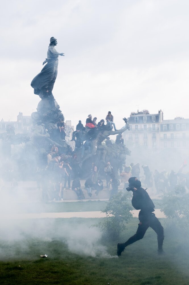 Demonstranten hocken auf einer Statur, die Szene in Protestnebel gehüllt