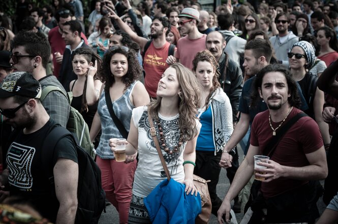 Eine Frau hält einen Becher Bier in der Hand, sie ist umringt von anderen Menschen
