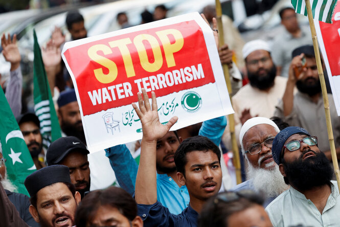 Demonstrierende halten Protestschilder, auf denen steht: STOP WATER TERRORISM, hoch