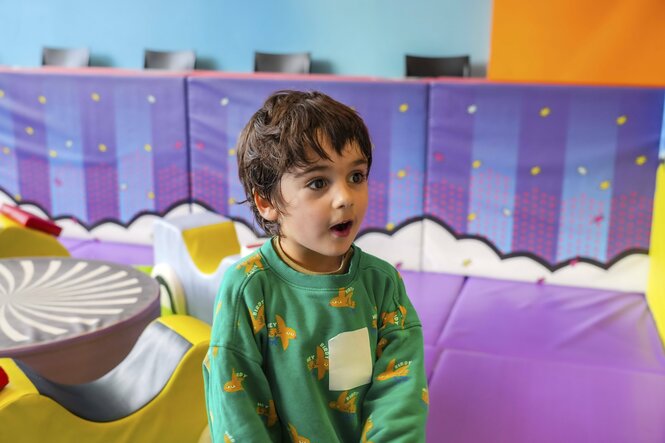 Kleiner Junge staunt beim Spielen in einem bunten und anregenden Indoor Spielplatz mit weichen Matten