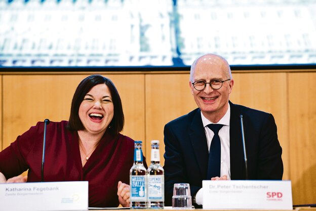 Eine Frau im roten Kleid und ein Mann im Anzug, beide lachen