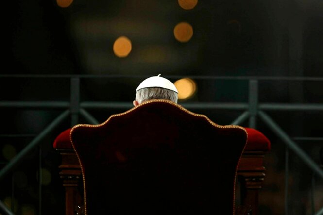 Papst Franziskus sitzt in einem Sessel, Rückenansicht, von ihm ist nur der Kopf mit der weissen Kopfbedeckung und Teild seiner Oberarme zu sehen