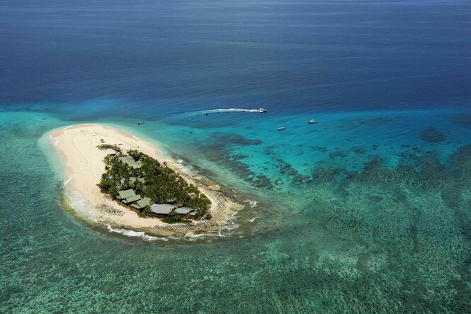 Eine kleine Insel im Pazifik, Luftaufnahme die zeigt, dass nur wenige Häuser auf der Insel stehen
