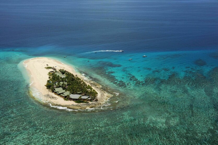 Eine kleine Insel im Pazifik, Luftaufnahme die zeigt, dass nur wenige Häuser auf der Insel stehen