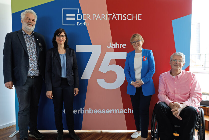 Vier Vertreter*innen des Berliner Paritätischen Wohlfahrtsverbandes vor einer Pressewand