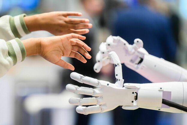 Kinderhände greifen nach Händen eines Roboters