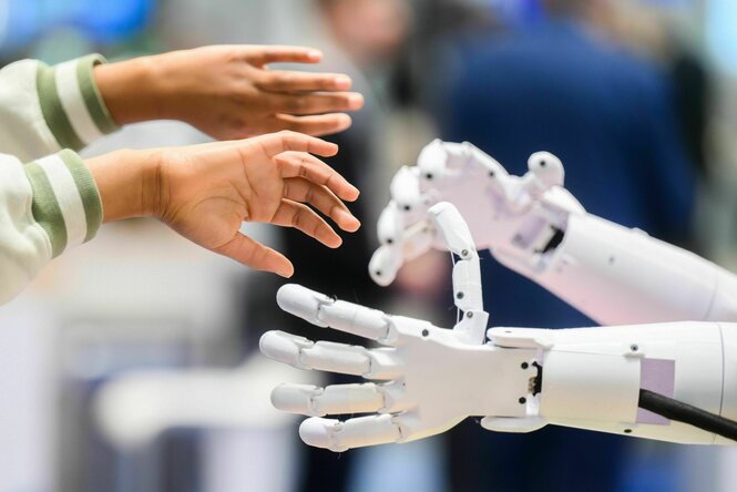 Kinderhände greifen nach Händen eines Roboters