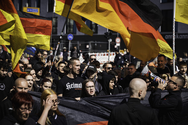 Deutschlandflaggen werden geschwenkt, die Teilnehmer tragen schwarze T-Shirts, auf einem steht "Heimat"