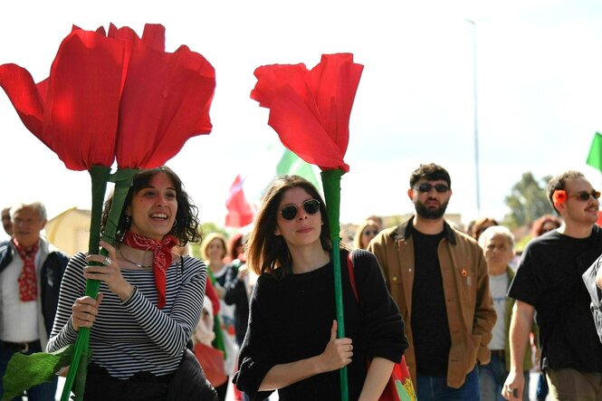 Zwei junge Frauen halten große Papier-Blumen mit roten Blüten in der Hand