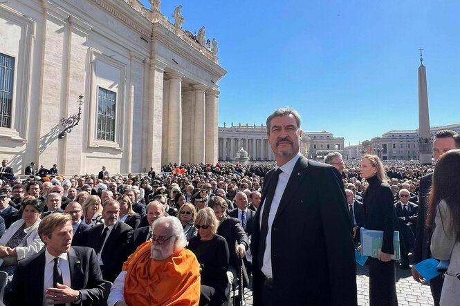 Markus Söder steht bei der Trauerfeier auf dem Petersplatz. Im Hintergrund Gäste aus aller Welt